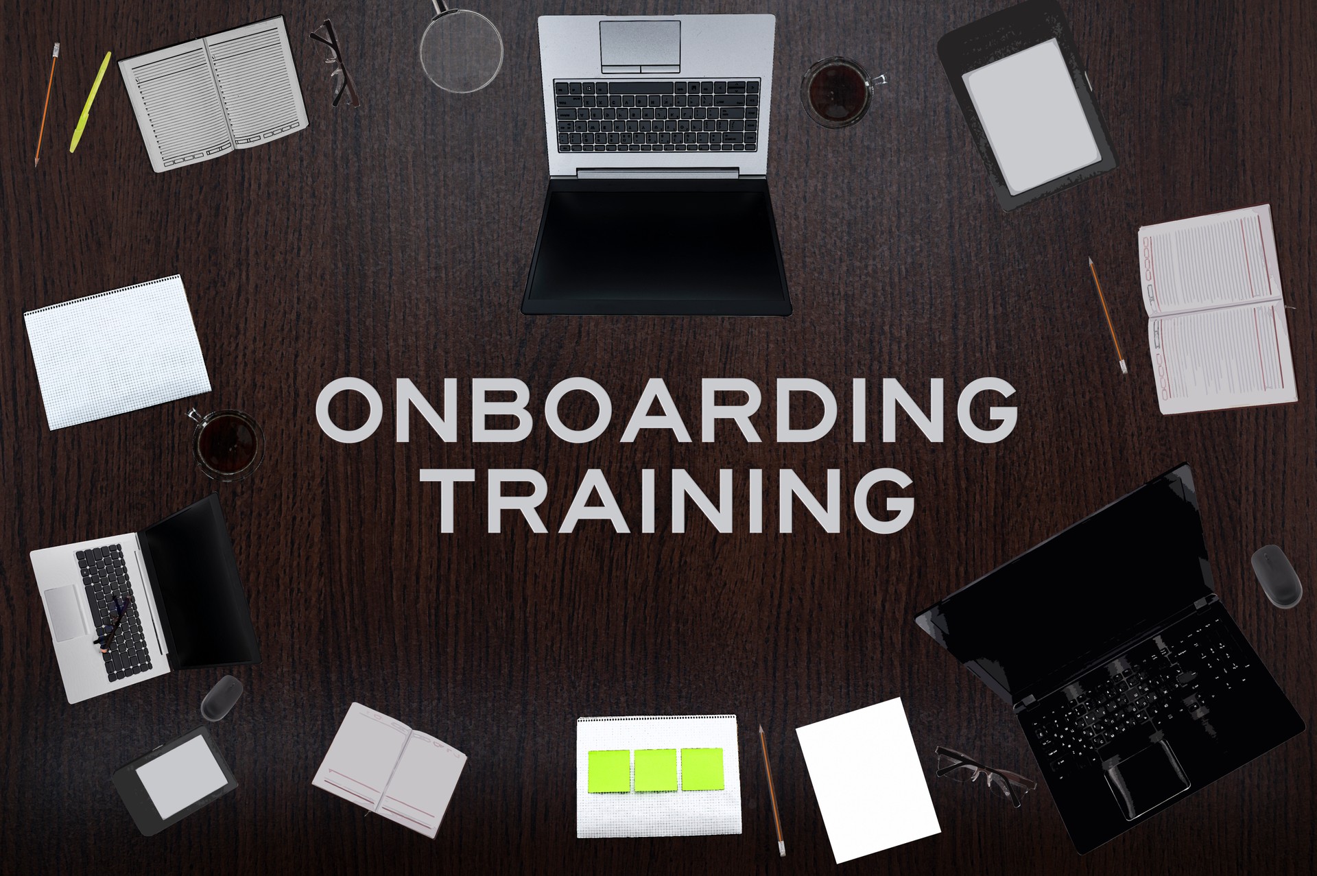 Top view of Onboarding training text on the table with laptops, notepad, coffee, eyeglasses, pens. Business concept.